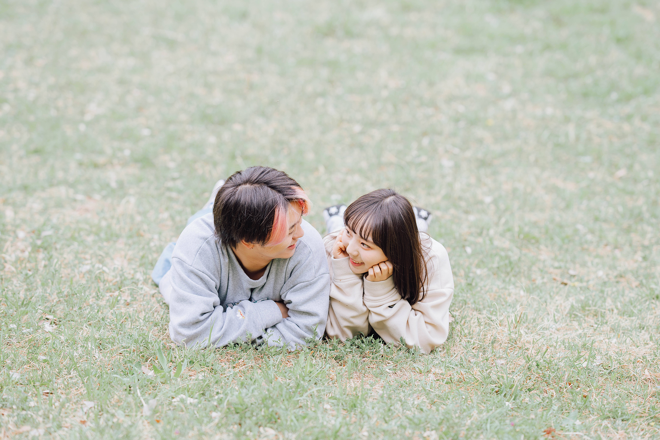 芝生に横たわり見つめ合うカップル